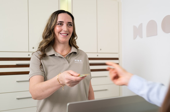 Mitarbeiterin der HNO-Praxis in Bruchsal reicht Patientin ein Terminkärtchen. 